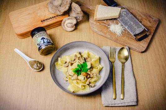 Bandnudeln mit cremiger Shiitake-Sauce auf einem Teller angerichtet, daneben die Zutaten (Parmesan, Shiitake Pilze, Miso). 