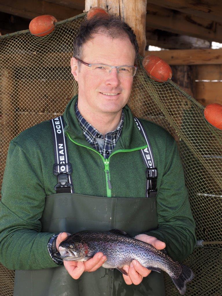 Klaus Decleva hält eine Forelle in den Händen von Delcevas Alpenfisch Mariazell