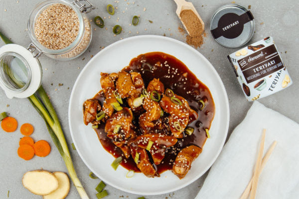 Saftiges Teriyaki-Chicken auf Teller serviert. Goldbraun glasiert, garniert mit Sesam und Frühlingszwiebeln, angerichtet mit Gemüse, regional & nachhaltig.